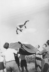 A Jewish child from Germany is tossed into the air on a blanket at a Kinderlager [children's recreational summer camp] in Horserod, Denmark.