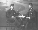 Studio portrait of two male Jewish students smoking cigarettes.