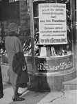 A woman reads a boycott sign posted in the window of a Jewish-owned department store.