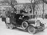 A group of SA members ride through the streets of Berlin in the back of a truck, exhorting Germans to boycott Jewish businesses.