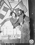 Mrs. Leopold Ruhalter, a Jewish survivor living in Vienna, looks on as her two-year old daughter, Renati, is given a special treat by Harry Weinsaft of the Joint Distribution Committee.