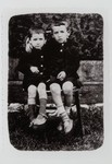 Two young boys share a chair.