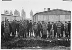 Group portrait of survivors standing next to the moat in the Dachau concentration camp following liberation.