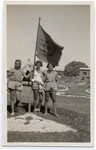 Noemi Bialer (right) poses with two friends beneath a Shomer Hatzair youth movement flag in a summer camp in Palestine.