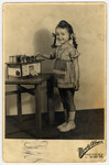 Sutdio portrait of a Hungarian Jewish girl standing next to a toy kitchen and pretending to cook.