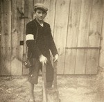 A Jewish youth wearing an armband poses holding a farm implement in the Kolbuszowa ghetto.