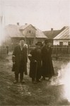 Three elderly Jews walk along an unpaved street in the Kolbuszowa ghetto.