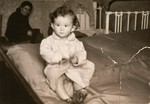 One-year-old Jurek Kaiser sits on a bed in his parents' apartment in the Kielce ghetto.