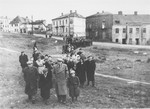 Survivors from Ostrowiec walk toward the site of a mass grave for 2000 Jews shot during the October 1942 action.