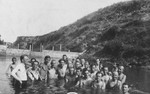 A group of Jewish young men pose together while swimming in a lake.