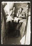 Two young Jewish women, one of whom is talking on the phone, sit in a private home in Opatow, Poland.
