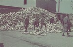 Workers stack wooden soles in a large pile in the Lodz ghetto wooden shoe factory.
