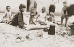 A group of children sits outside in the Rivesaltes internment camp.