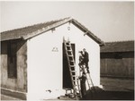 Joseph paitns the exterior walls of the Secours Suisse barracks.