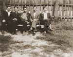 Five Jewish high school friends pose outside on a bench in front of a fence in Brody, Poland.