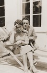 A Jewish couple poses outside on a veranda.  

Pictured are Jacob and Czeslava (Harmelin) Sauber.