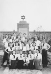 Group portrait of a Zionist youth organization in Zeilsheim standing in front of a memorial to victims of the Holocaust.