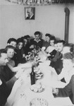 Members of a Zionist youth group in Zeilsheim gather for a celebration around a table laden with food and beverages.