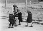 A Jewish woman walks towards the gas chambers with three young children and a baby in her arms, after going through the selection process on the ramp at Auschwitz-Birkenau.