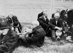 Elderly Jewish men from Subcarpathian Rus sit on the grass in Auschwitz-Birkenau prior to being sent to the gas chambers.