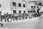 A group of men who have been rounded-up for deportation, are marched out of town [probably by members of the Ustasa militia].