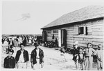 Children, some of whom are dressed in Ustasa uniforms, stand outside a barracks in the Gornja Rijeka concentration camp.