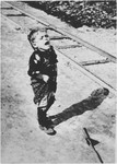 A little boy standing next to a train track cries out for help.