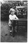 Portrait of a Jewish toddler holding onto a chair in the garden of a home in Frankfurt am Main, Germany.