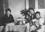Members of the Magid family sit around a table set with a tea service.