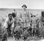 Ernest Berg and his son Philip, Jewish refugees from Germany, pose in a pyrethrum field in Limuru, Kenya, with their African farmhands.