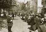 Jewish deportees, carrying a few personal belongings in bundles and suitcases, march through town along the Hindenburgstrasse from the assembly center at the Platzscher Garten to the railroad station.