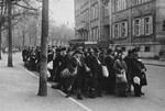 Jewish deportees, carrying a few personal belongings in bundles and suitcases, march through town from the assembly center at the Platzscher Garten to the railroad station.