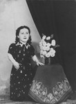 Portrait of a member of the Ovici family, a family of Jewish dwarf entertainers known as the Lilliput Troupe, who survived Auschwitz, next to a vase of flowers.