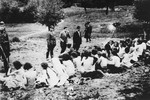 German police and auxiliaries in civilian clothes look on as a group of Jewish women are forced to undress before their execution.
