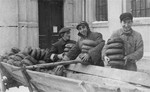 Jewish men and youths remove loaves of bread from a wagon at the soup kitchen in the Kielce ghetto.