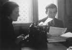 Two members of the ghetto administration sit at a desk in the office of the Judenrat in the Kielce ghetto.