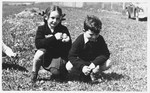 Two Czech Jewish children pose outside in a grassy field.
