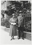 Louis and Margarethe Wilhelm pose on a sidewalk next to a rod iron fence.
