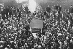 An automobile in which Adolf Hitler is riding moves through a crowd of supporters as it leaves the Chancellery after Hitler's meeting with President Paul von Hindenburg.