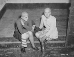 Two young women charged with collaboration sit in a jail cell after their hair was shorn by members of the resistance.