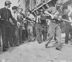 Members of the French resistance lead a wounded collaborator away from a crowd after he was beaten in the street on the day Paris was liberated.