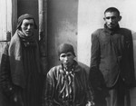 Three survivors pose outside a barracks in the Dachau concentration camp immediately after the liberation.