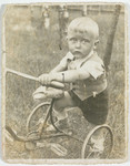 Portrait of a young Jewish boy on a tricycle in Lodz Poland.