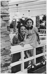 A woman and her daughter pose on the railing of a porch in prewar Poland.