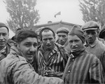 Close-up portrait of survivors of the Dachau concentration camp, one of whom is holding a cigarette.