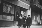 An extended Jewish family poses in front of a store plastered with posters in Berlin.