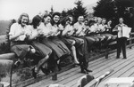 Members of the SS Helferinnen (female auxiliaries) and SS officer Karl Hoecker sit on a fence railing in Solahuette eating bowls of blueberries.