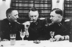 Three SS officers gather for drinks in a hunting lodge.