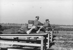 Karl Hoecker shoots his rifle while lying on a wooden table during target practice.