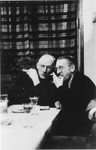 Two Germans converse at a table at a hunting lodge.